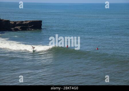 Vista aerea del surfista sulla superficie blu dell'oceano indiano. Cavalcare le onde. Spiaggia di Batu Bolong sulla costa rocciosa dell'isola di Bali, Indonesia. Surfista al Foto Stock