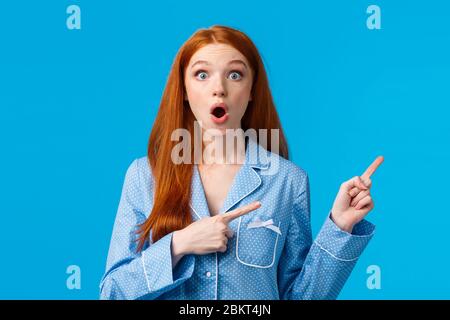 Sorpresa startled ragazza rossa ha scoperto l'offerta speciale, sconto promo, punta angolo superiore destro, indossare l'abbigliamento da notte, gossiping circa sleepover Foto Stock