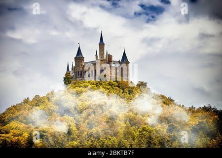 Castello su una montagna boscosa nella nebbia sotto le nuvole, Hohenzollern, Germania Foto Stock