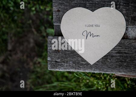 Ti amo mamma scritta su una carta su una vecchia panchina rustica Foto Stock