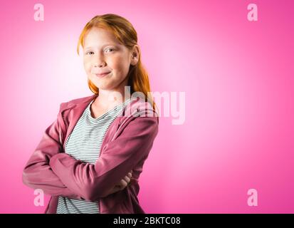 Ritratto giovane sicuro bianco Schoolgirl su sfondo Pink Studio con spazio di copia. Forte indipendente posa piccola ragazza teenager pre. 10 anni Foto Stock