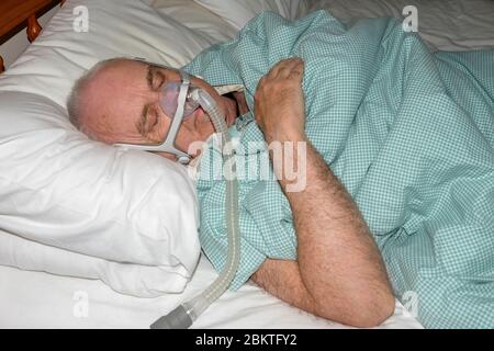 Maggio 2020 - uomo maturo addormentato veloce indossare la maschera di una macchina CPAP sonno apnea @4.15 Foto Stock