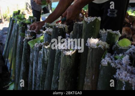 Lhokseumawe, Aceh, Indonesia. 5 maggio 2020. Lavoratori che mettono riso glutinoso e alcune altre spezie, in bambù per fare lemang durante Ramadan.Lemang è uno dei cibi popolari in Aceh, come un menu iftar nel mese santo di Ramadhan, dove i musulmani in tutto il mondo digiunano dall'alba al tramonto per un mese intero. Credit: Maskur has/SOPA Images/ZUMA Wire/Alamy Live News Foto Stock