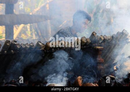 Lhokseumawe, Aceh, Indonesia. 5 maggio 2020. I lavoratori bruciano il bambù di lemang durante il Ramadan.Lemang è uno dei cibi popolari in Aceh, come un menu iftar nel mese santo del Ramadhan dove i musulmani intorno al mondo digiunano dall'alba al tramonto per un mese intero. Credit: Maskur has/SOPA Images/ZUMA Wire/Alamy Live News Foto Stock