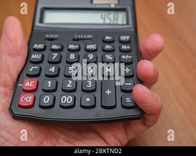 5 primo piano della mano umana con una calcolatrice nera con messa a fuoco selettiva e profondità di campo bassa Foto Stock