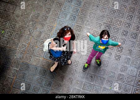 Madre e figlio tornano a casa indossando maschere facciali protettive. Foto Stock