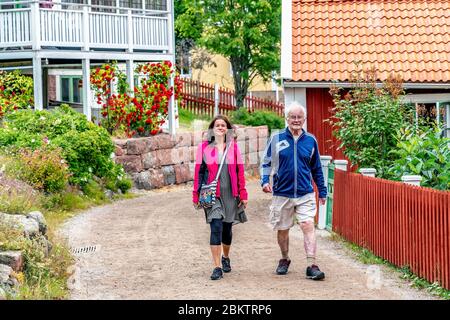 ULVON, SVEZIA - 23 LUGLIO 2019: Giovani donne scandinave camminano con l'uomo anziano, turisti camminano sull'isola di Ulvon, luogo storico di pesca nel Mar Baltico Foto Stock