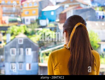 Giovane donna che le ha aggrappato le mani sul balcone per showi gratitudine a tutti gli operatori sanitari durante l'epidemia di coronavirus. Molte case colorate. Foto Stock