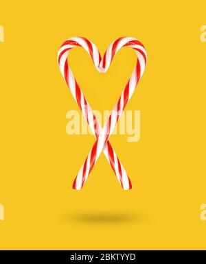 Lollipop personale di Natale su sfondo giallo. Canna di caramella dura a righe rosse e bianche. Natale sfondo. Concetto di negozio di caramelle. Caramelle di Natale Foto Stock