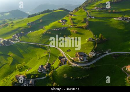 Veduta aerea di improbabili prati verdi delle Alpi Italiane, verdi pendici delle montagne, Bolzano, enormi nuvole su una valle, tetti di case Foto Stock