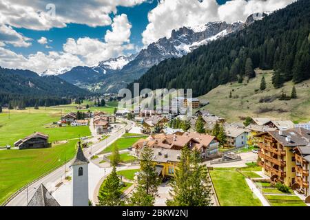 Veduta aerea della valle con Chalet, verdi pendici delle montagne d'Italia, Trentino, Fontanazzo, enormi nuvole su una valle, tetti di case di Foto Stock