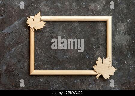 Telaio in legno e foglie di acero tagliate su sfondo muro scuro. Autunno, autunno vacanza concetto. Disposizione piatta, vista dall'alto, spazio per la copia Foto Stock