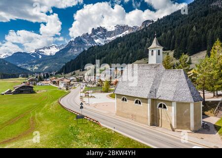 Veduta aerea della valle con Chalet, verdi pendici delle montagne d'Italia, Trentino, Fontanazzo, enormi nuvole su una valle, tetti di case di Foto Stock