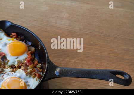 Sfondo alimentare, uova fritte con verdure in padella su tavola di legno, fuoco selettivo Foto Stock