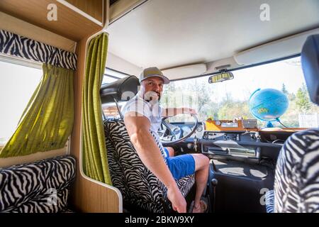 Ritratto di uomo disinteressato durante le vacanze seduto nel suo furgone guardando un globo Foto Stock
