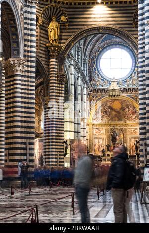 SIENA, ITALIA - 13, MARZO, 2018: Foto a lunga esposizione di turisti commoventi all'interno della Cattedrale cattolica di Siena, uno dei migliori luoghi di Siena Foto Stock