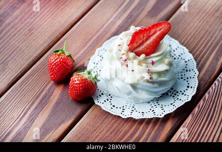 Dolce Pavlova meringa con fragole fresche, crema su sfondo rustico in legno. Foto Stock