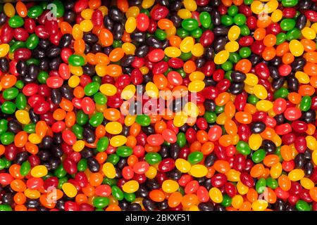 Assortiti colorati fagioli di gelatina nero, rosso, verde, giallo e arancione, dolci sfondo caramella, cibo spazzatura bambini. Foto Stock