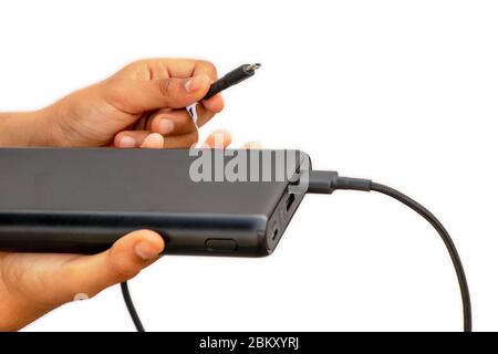 Mani che mostrano il caricabatterie (Power bank) con cavo di ricarica usb bianco isolato su sfondo bianco Foto Stock