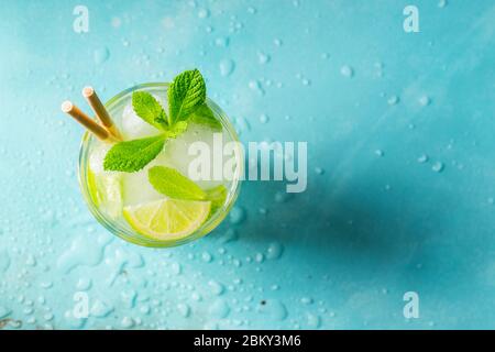 Cocktail di limonata o mojito fatti in casa con cubetti di lime, menta e ghiaccio in un bicchiere su un tavolo di pietra chiaro. Drink estivo fresco. Vista dall'alto con spazio per le copie. Foto Stock