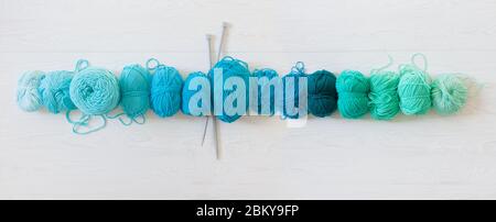Filato per maglieria acquamarina, verde, blu e turchese. Bianco legno lungo sfondo Foto Stock