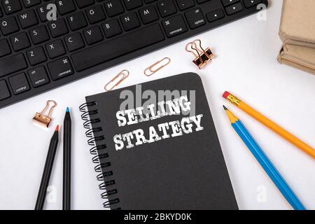 STRATEGIA DI VENDITA. Marketing, business, conoscenza e concetto di successo. Notebook nero e tastiera del computer su una scrivania bianca per ufficio Foto Stock