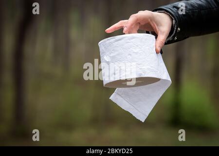 Mano donna che tiene rotolo di carta di tessuto. Igiene, pulizia ed ecologia. Verde foresta sullo sfondo Foto Stock