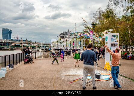 Londra / UK - Settembre 4 2015: I bambini giocano e cercano di prendere le bolle sapone, mentre i loro genitori scattare foto, a Southbank. Foto Stock