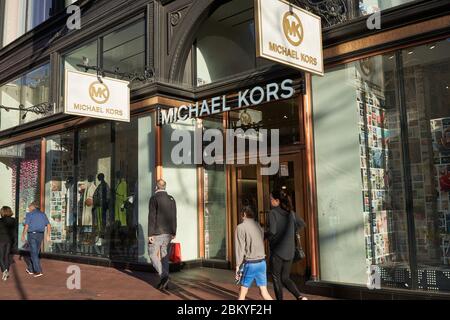 Gli amanti dello shopping passeggiando accanto al negozio Michael Kors in Market Street a San Francisco. Il marchio della moda è di proprietà di Capri Holdings Limited. Foto Stock