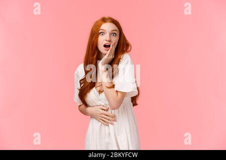 Girovita ritratto sorpreso e curioso, stupito redhead ragazza sentito sorprendente notizie, pettegolezzi con la ragazza in festa, bocca aperta impressionato, tocco Foto Stock