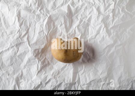 Brutto patata in forma di cuore su carta bianca artigianale sbriciolata. Concetto ambientale vegetale non normale Foto Stock