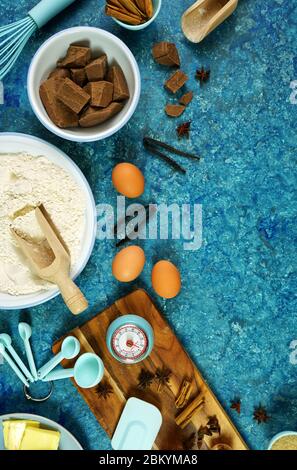 Cottura flatlay composizione creativa vista dall'alto per ricette al cioccolato tra cui uova, farina, burro e spezie, con accessori da cucina su textu vintage Foto Stock