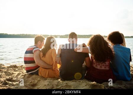 Vista posteriore dei giovani che si raffreddano all'esterno Foto Stock