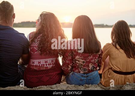 Vista posteriore dei giovani che si raffreddano all'esterno Foto Stock