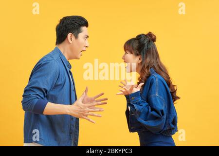 Profilo vista laterale ritratto di due persone nervose aggressive arrabbiate attraente che hanno combattere la rabbia colpa isolato sopra brillante brillante sfondo arancione Foto Stock