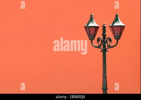 Lampione vintage nero contro la vibrante parete di cemento arancione Foto Stock
