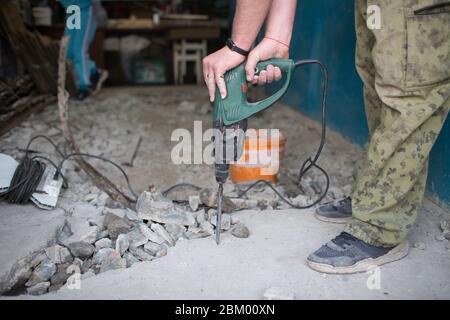 Uomo che martella il pavimento con un martello a mano Foto Stock