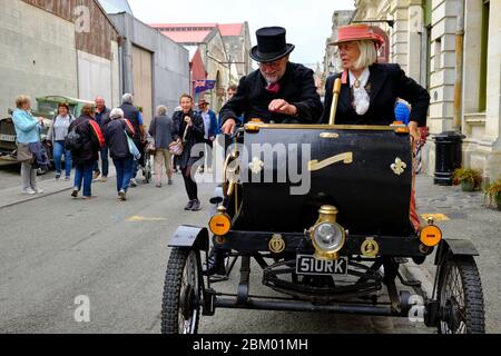 Coppia senior che viaggia in un'auto vittoriana d'epoca per le strade di Oamaru durante una fiera a tema. Foto Stock