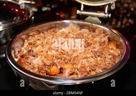 Ampia porzione di Takoyaki di stile giapponese con fiocchi di bonito essiccati sopra in un vassoio a buffet Foto Stock