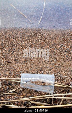 tazza di plastica trasparente rotta sulla spiaggia Foto Stock