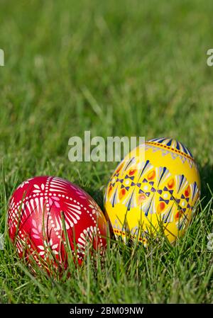 Due uova di Pasqua dipinte a mano giacciono nell'erba in formato ritratto Foto Stock