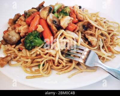 Pasta con verdure, funghi e pollo su un piatto bianco. Foto Stock