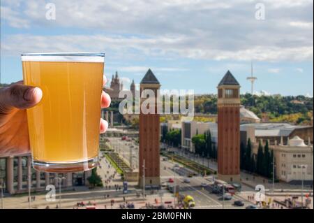 Bicchiere di birra con vista su Piazza Spagna a Barcellona, Spagna. Uomo che tiene un bicchiere di birra fredda di grano chiaro. Foto Stock