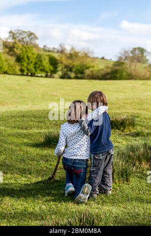La sorella maggiore e il fratello minore abbracciano il paesaggio di primavera, in Inghilterra Foto Stock