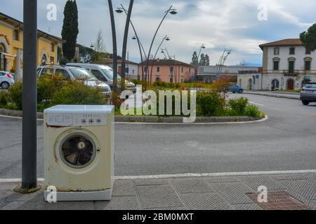 La lavatrice abbandonata, vecchia, arrugginita, strappata, è rimasta in un parcheggio nel centro città. Scenario di inquinamento e discarica illegale di rifiuti sulla proprietà della città Foto Stock