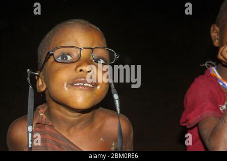 Giovane Maasai bambino all'ingresso di una capanna. Maasai è un gruppo etnico di persone semi-nomadi fotografate in Kenya Foto Stock