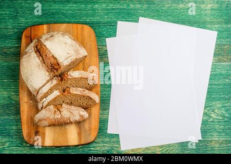 Senza lievito, senza impasto, senza lievito sano grano di segale organico mezzo affettato pane fatto in casa pane pane a bordo cucina sul tavolo di legno verde. Foto Stock