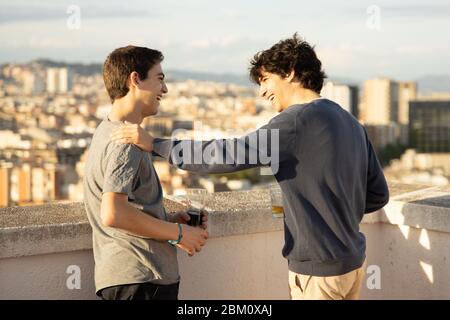 Due giovani che bevono mentre parlano sul tetto Foto Stock