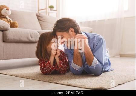 Bel papà e la sua ragazza liitle che si stesa sul pavimento Foto Stock