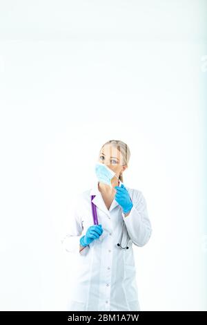 l'infermiere del medico mette su una maschera protettiva. Un infermiere in una maschera respiratoria. Indossare le maschere. Indossare guanti. Bello medico biondo mostra come indossare un protec Foto Stock